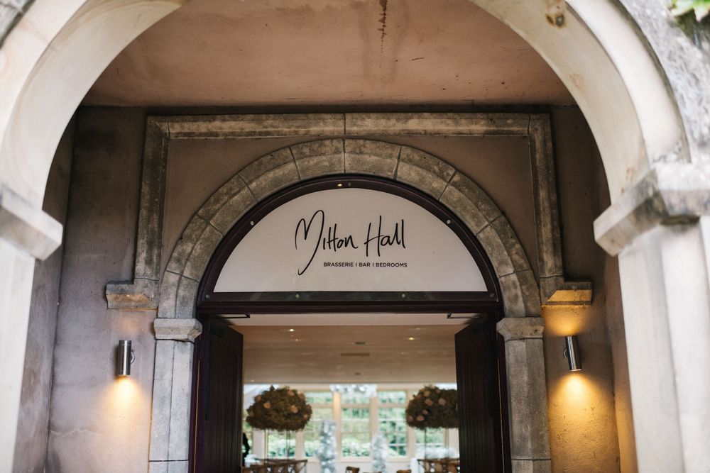 Elegant stone archways with hanging lights create a romantic entrance to an outdoor dining patio at a restaurant.