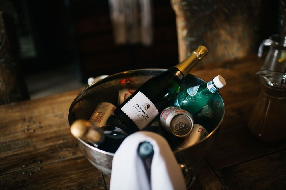Elegant wine and champagne bottles displayed on rustic wooden surface for wedding reception.