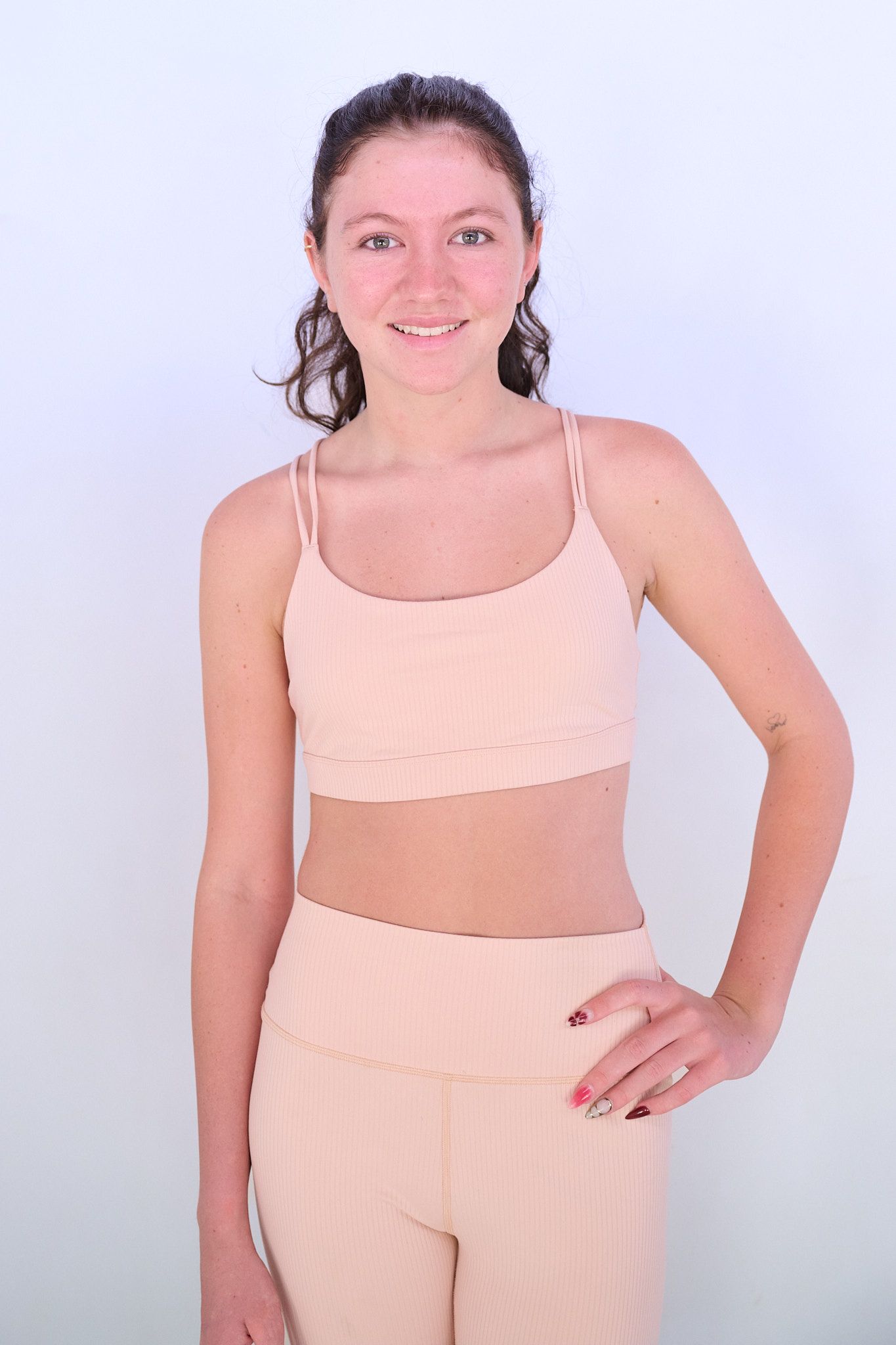 Model poses in white crop top and denim against light blue background in series of artistic fashion shots.