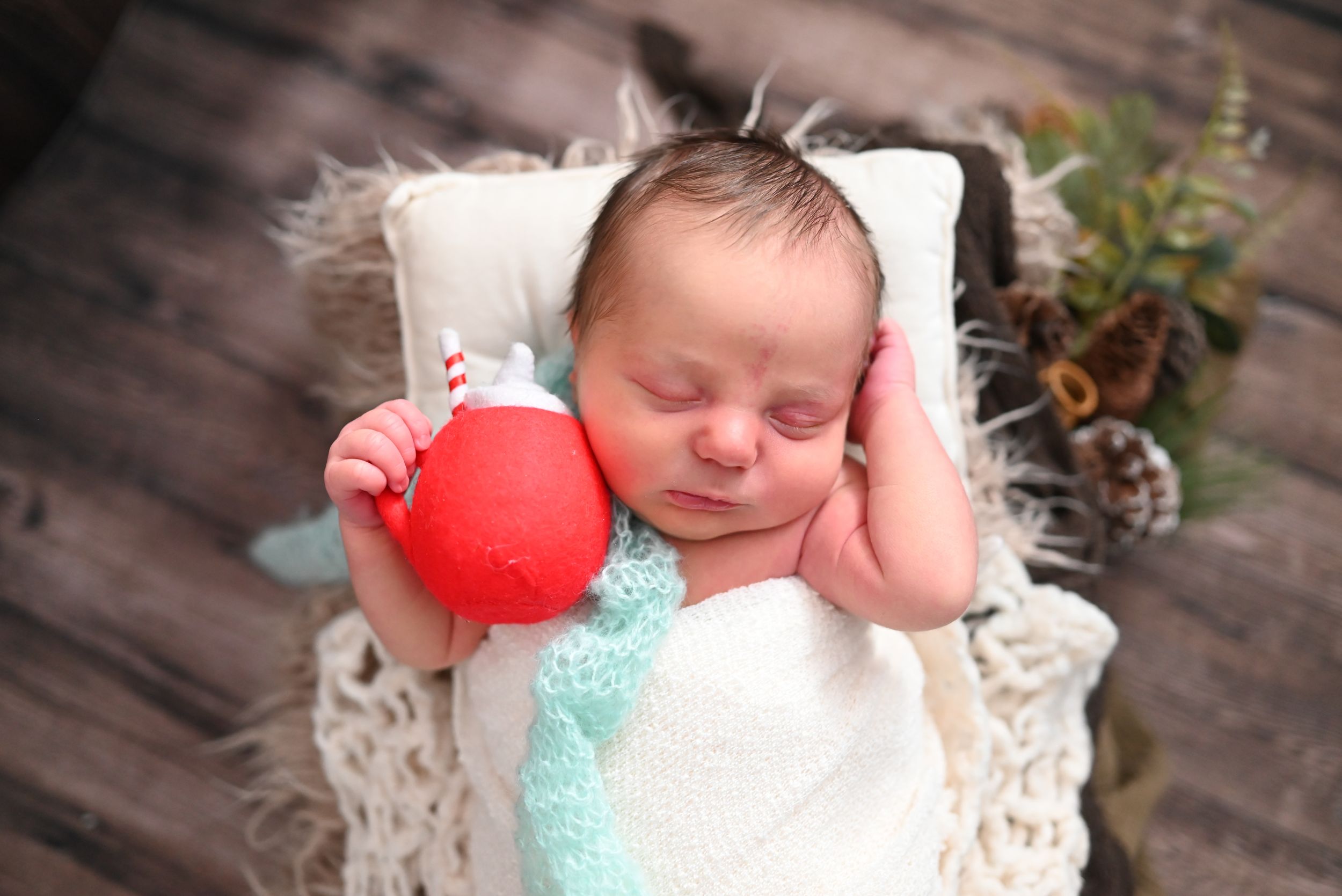 A newborn baby rests peacefully on white lace fabric while wearing a soft knit hat.
