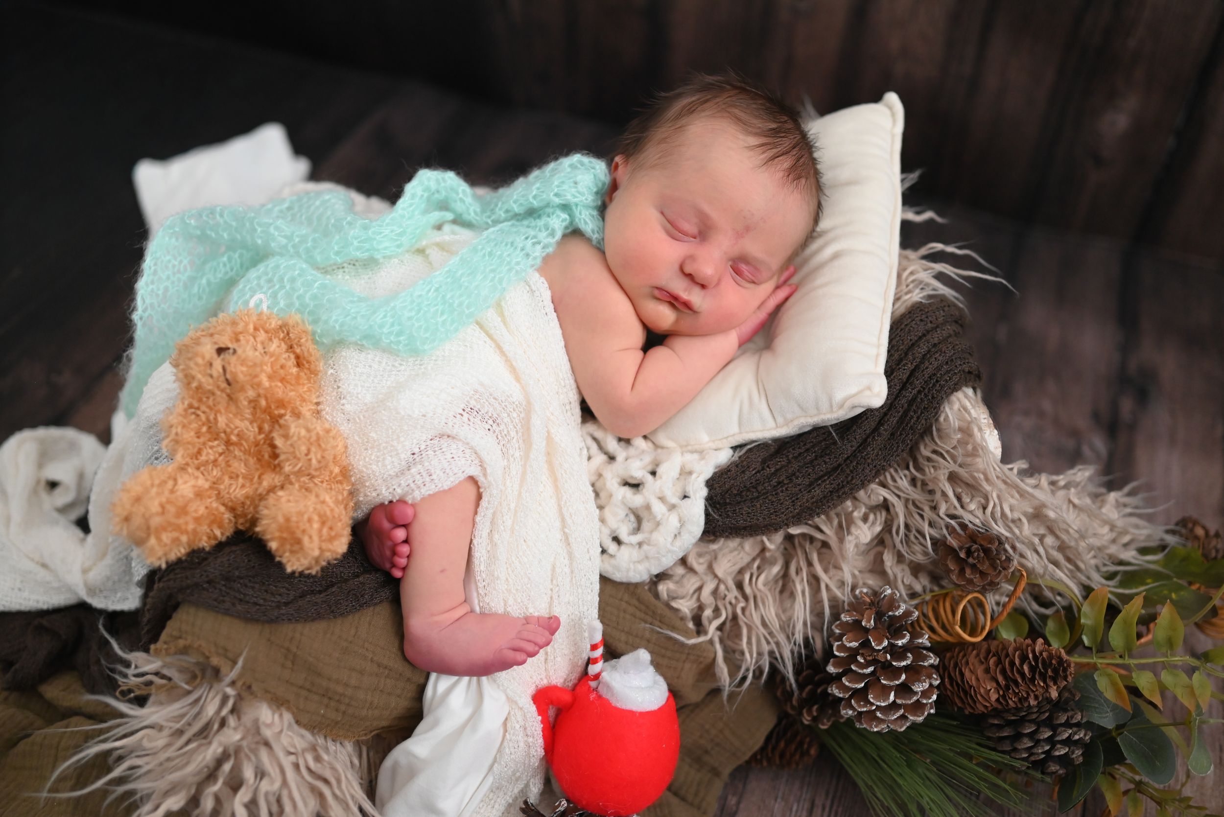 A sleeping baby in white clothing lies peacefully on a cozy bed with plush toys and soft blankets.