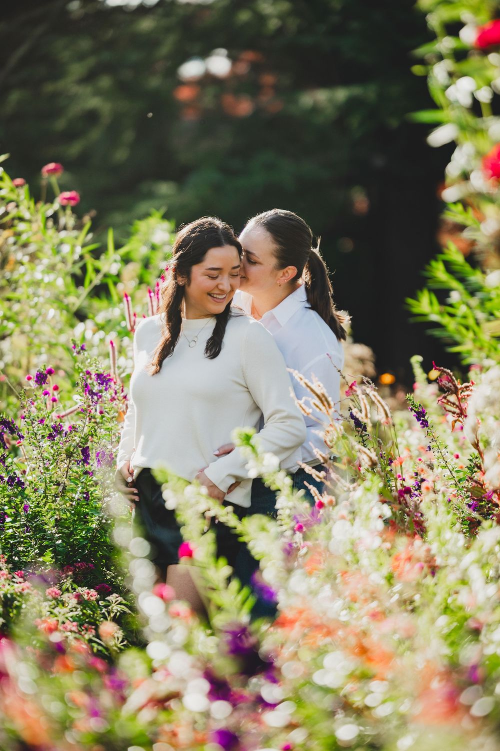 A romantic couple shares tender moments in a vibrant garden filled with colorful summer blooms and flowers during a dc proposal photoshoot
