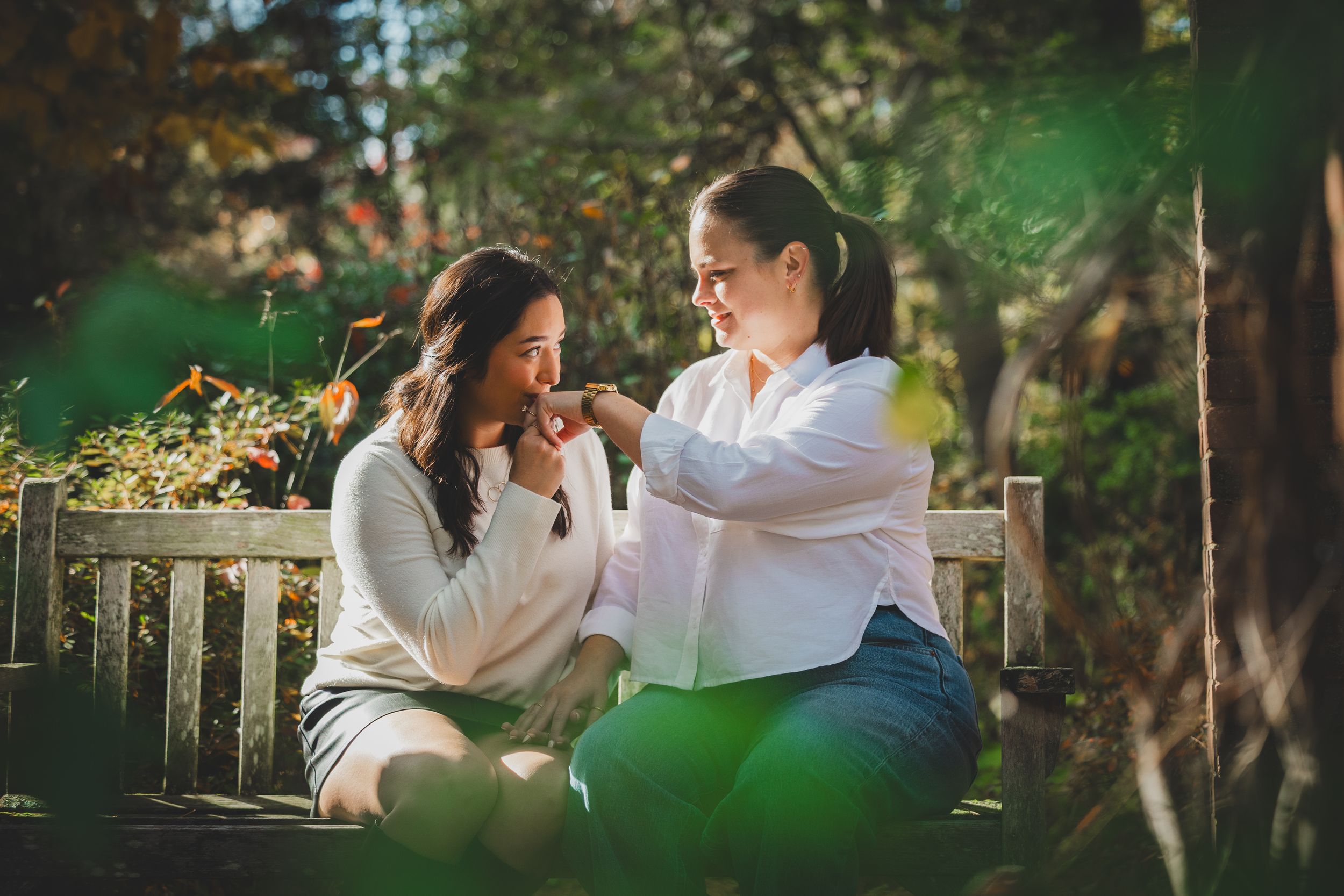 A couple in white outfits shares intimate moments in a romantic outdoor proposal photoshoot at Hillwood Estate