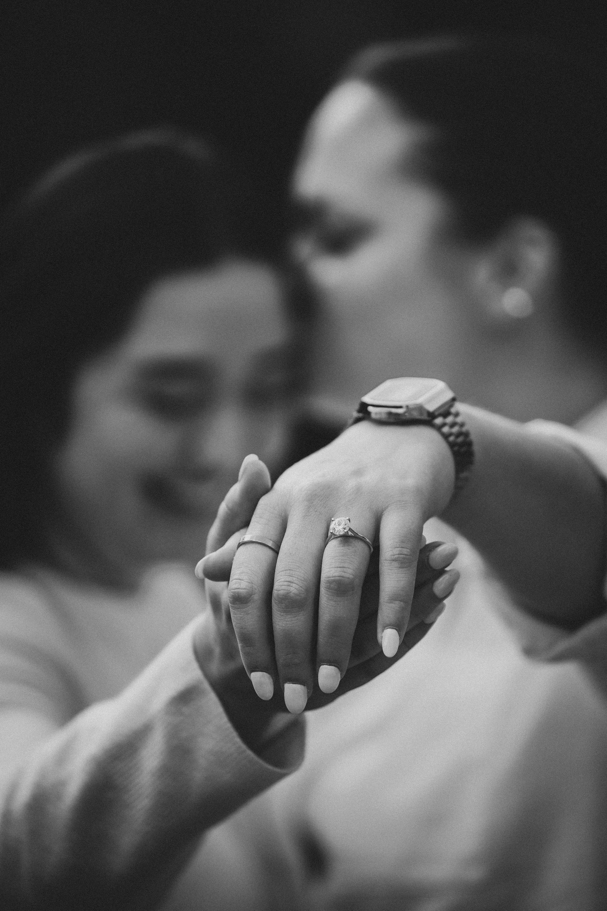Close-up black and white photo showing hands with engagement ring in romantic sequence.