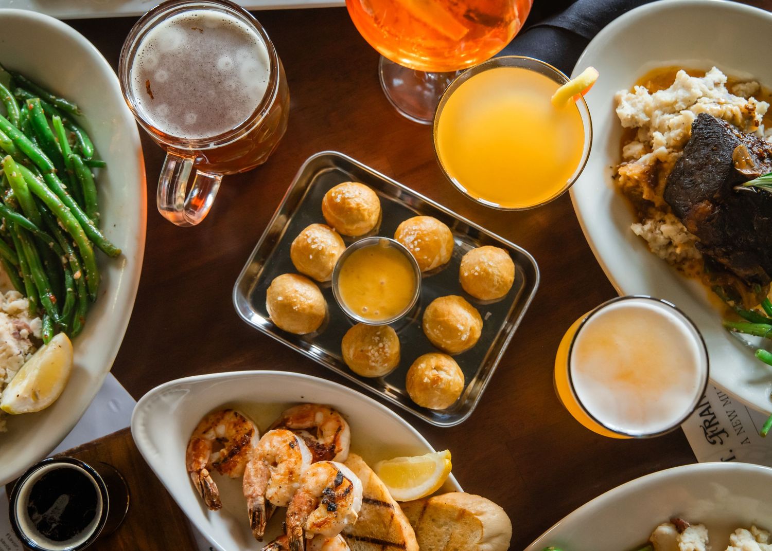 Overhead view of a restaurant table filled with various dishes including seafood, vegetables, drinks and appetizers.