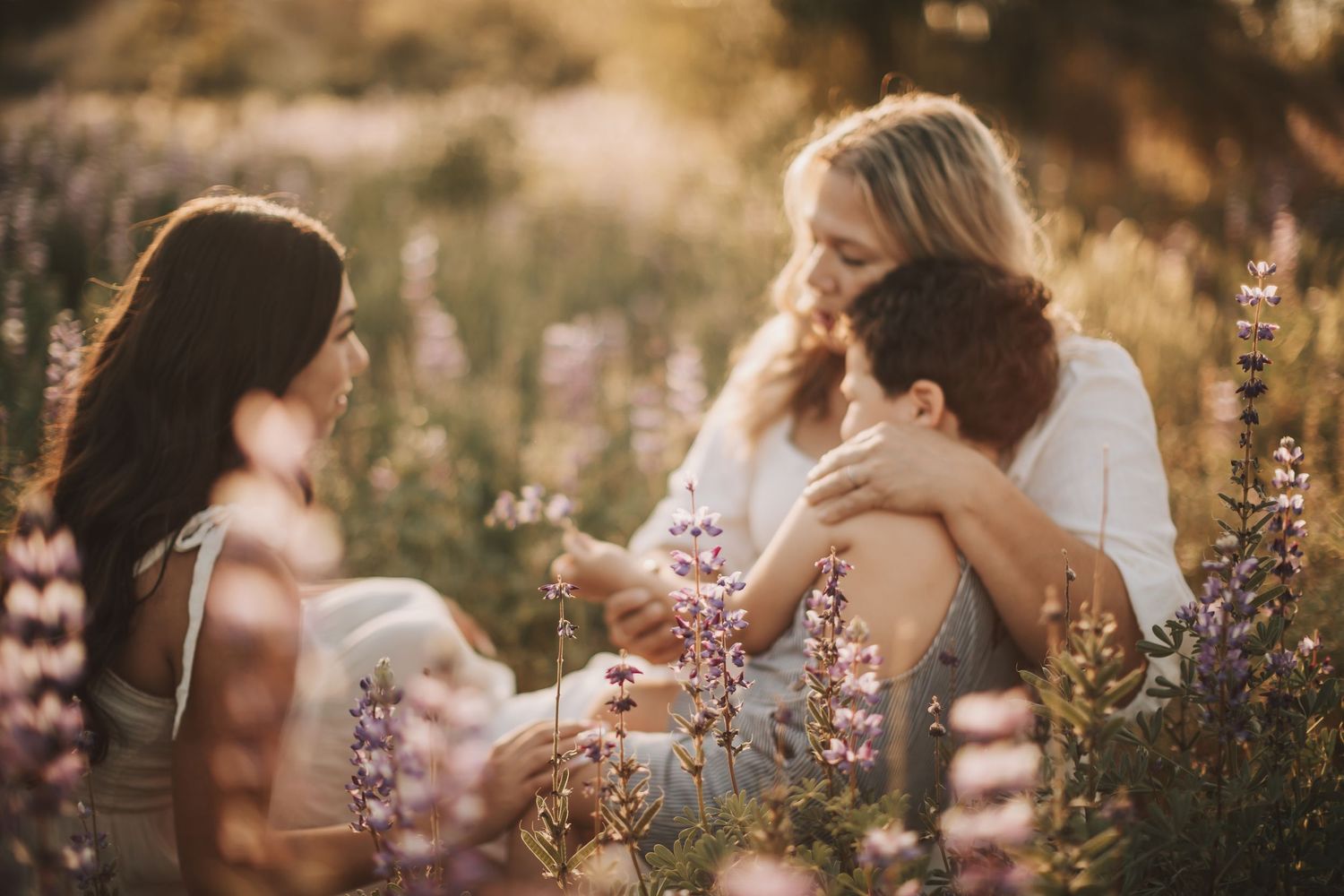 A couple embraces in a golden sunlit field with wildflowers during sunset creating a romantic silhouette.