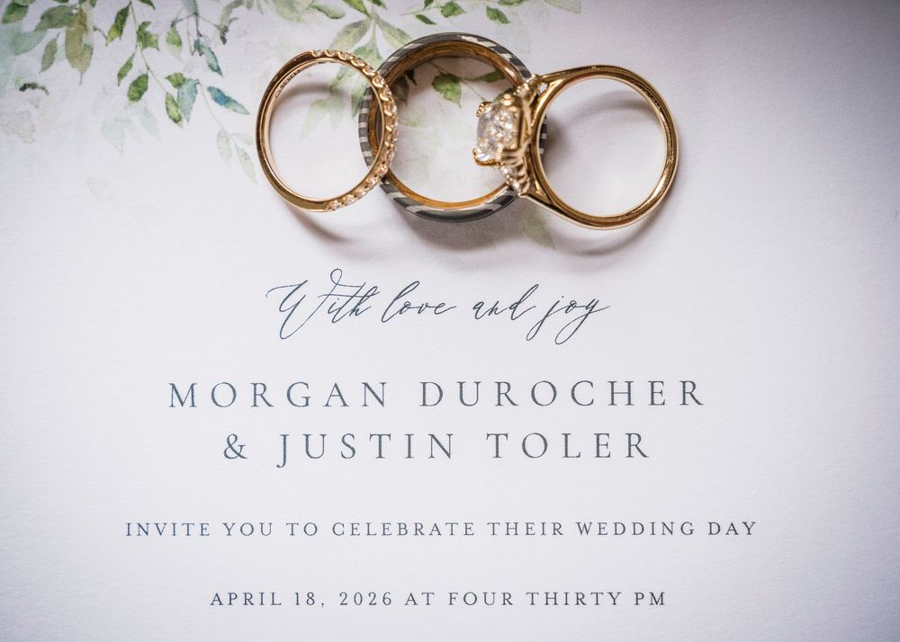 Elegant wedding invitation for Morgan Durocher and Justin Toler featuring gold rings and greenery accents.