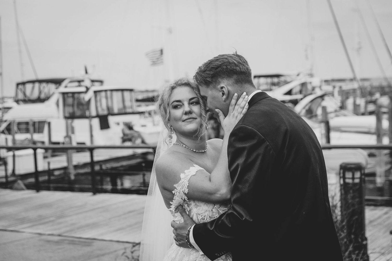 A romantic black and white wedding photo showing intimate moments between a bride and groom at a marina in Northport Michigan.