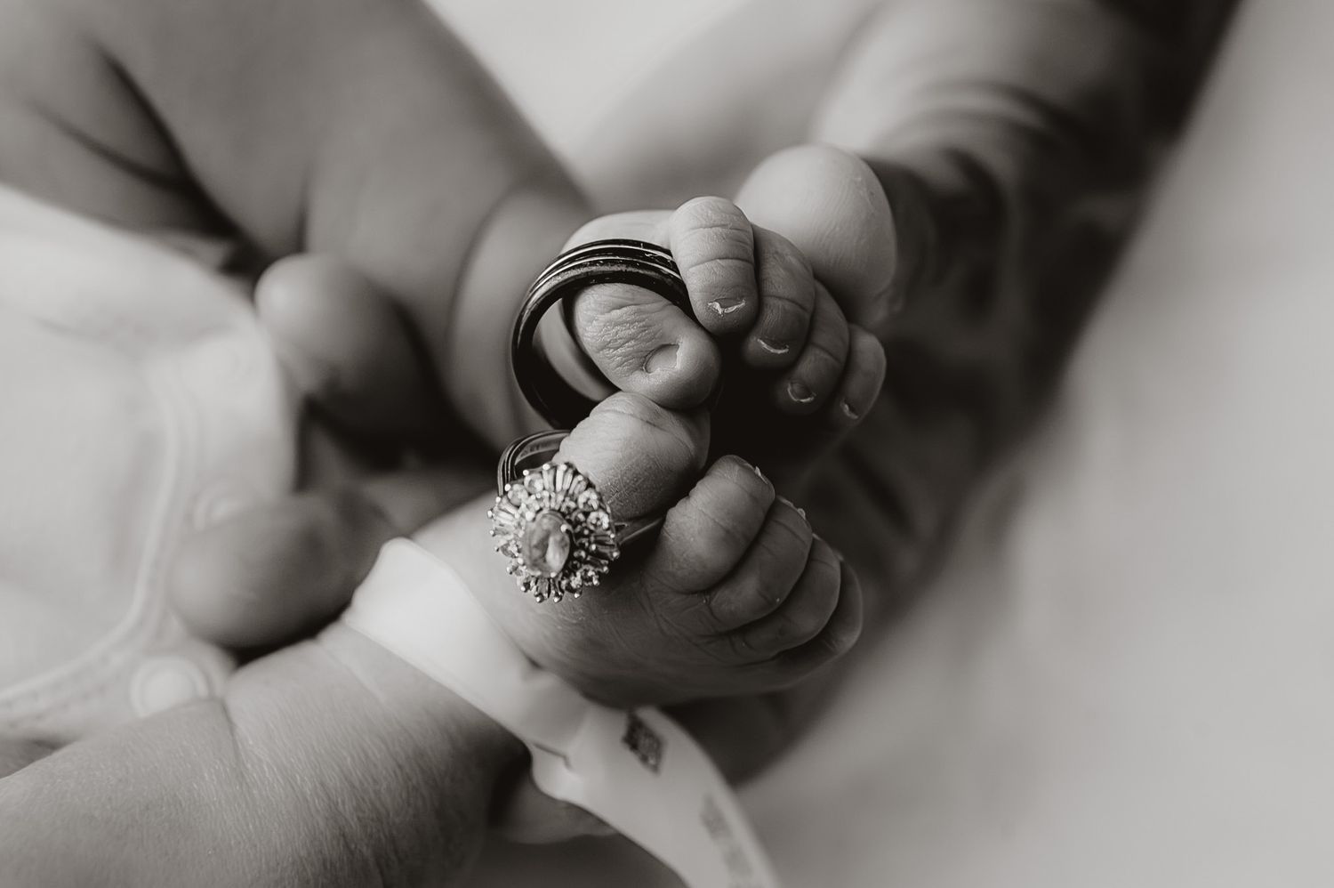 Black and white close-up photos showing hands holding a delicate engagement ring.
