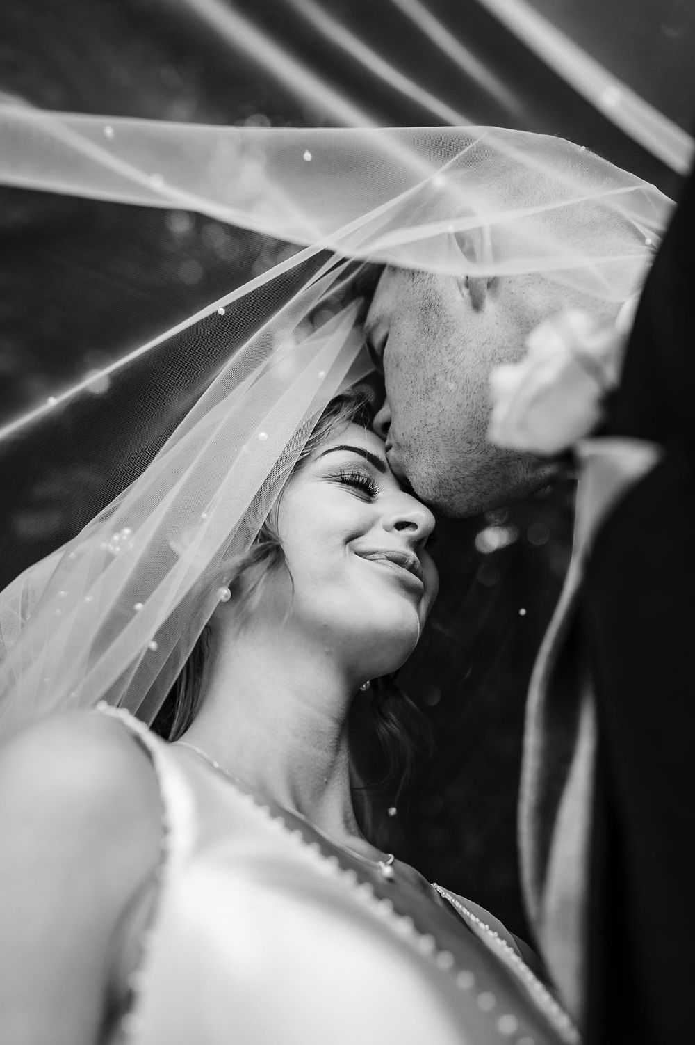 A series of black and white wedding photos showing romantic moments between a bride and groom under a veil.