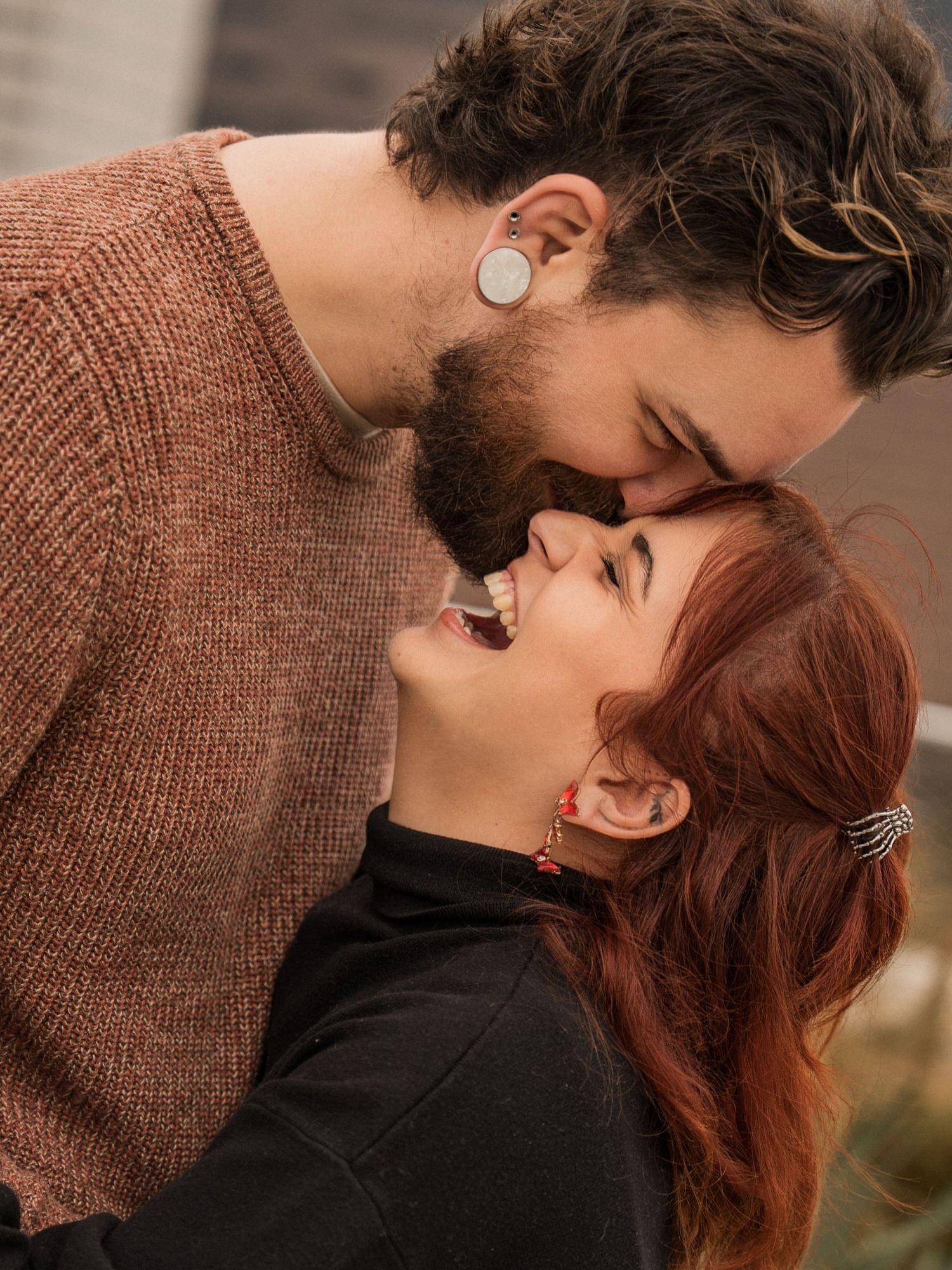 Romantic couple sharing an intimate moment outdoors, with one wearing a brown knit sweater and the other in black.