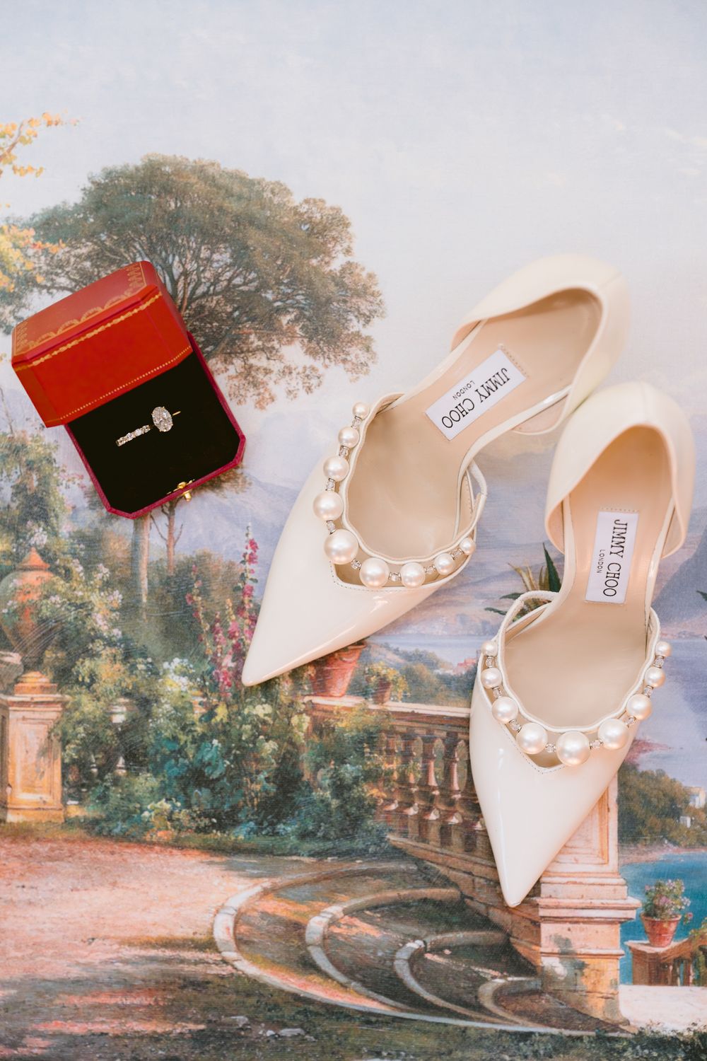 Elegant cream-colored Jimmy Choo bridal shoes with pearl embellishments displayed against a romantic garden backdrop.