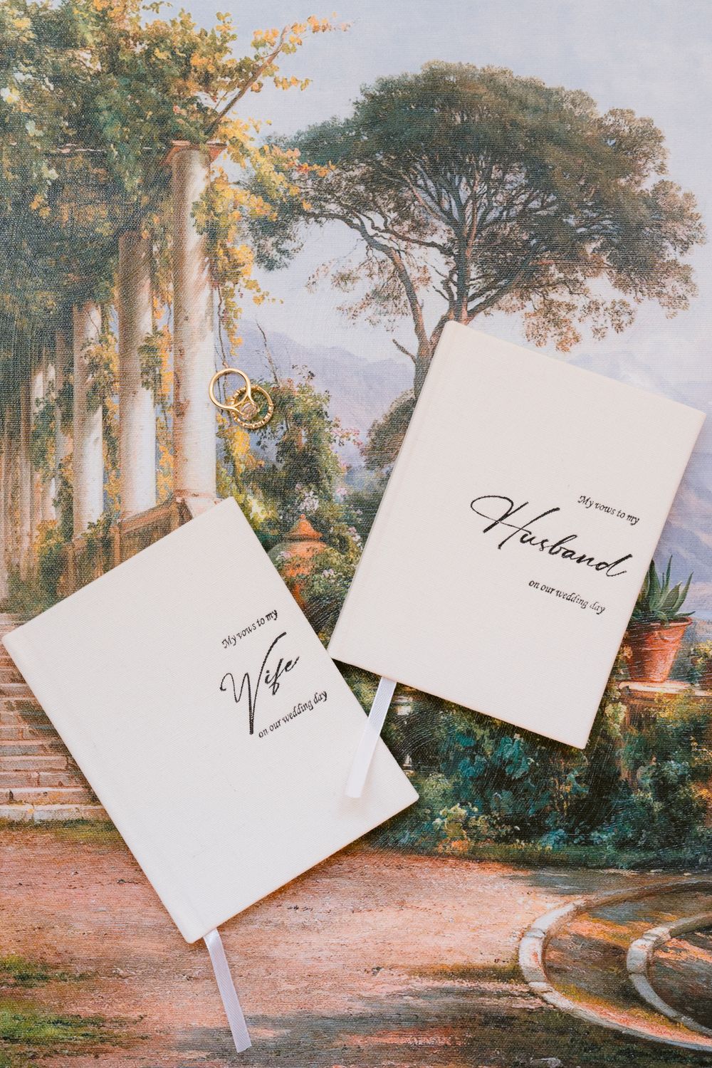 Elegant wedding invitation cards arranged artistically on a romantic garden landscape painting background.