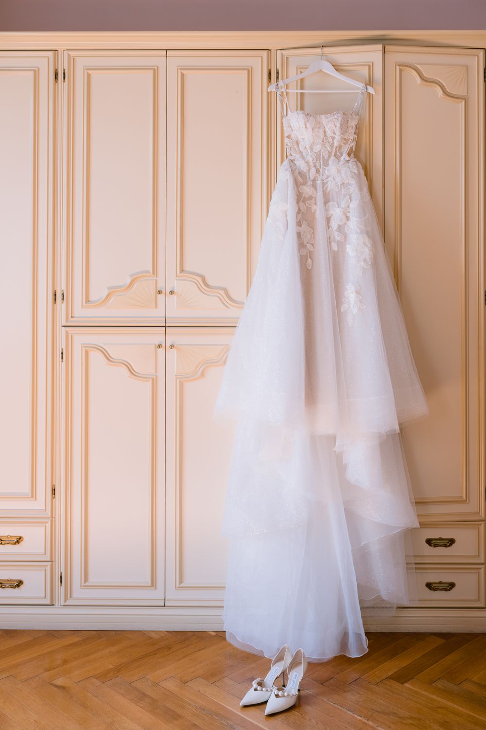 White wedding dress and shoes displayed elegantly against cream-colored paneled closet doors.