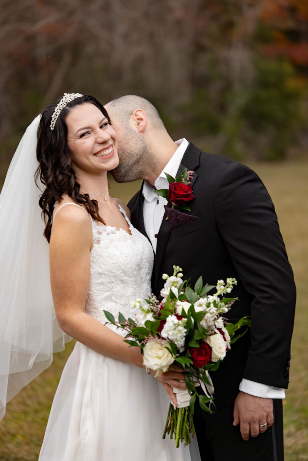 A joyful wedding moment captured with a beautiful bouquet of red and white flowers.