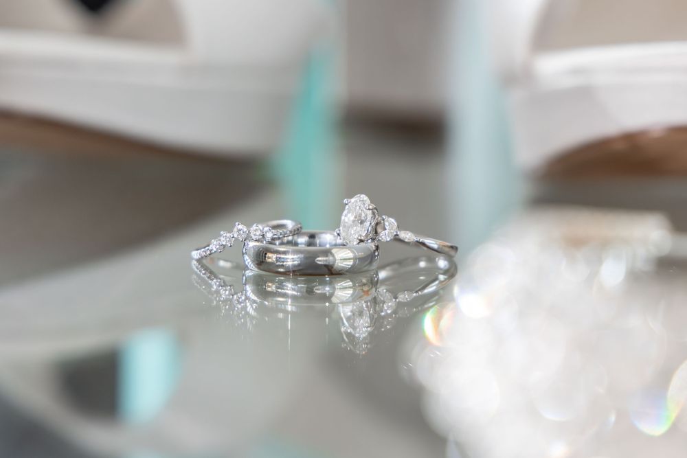 Close up macro photography of a sparkling diamond engagement ring on a reflective surface.
