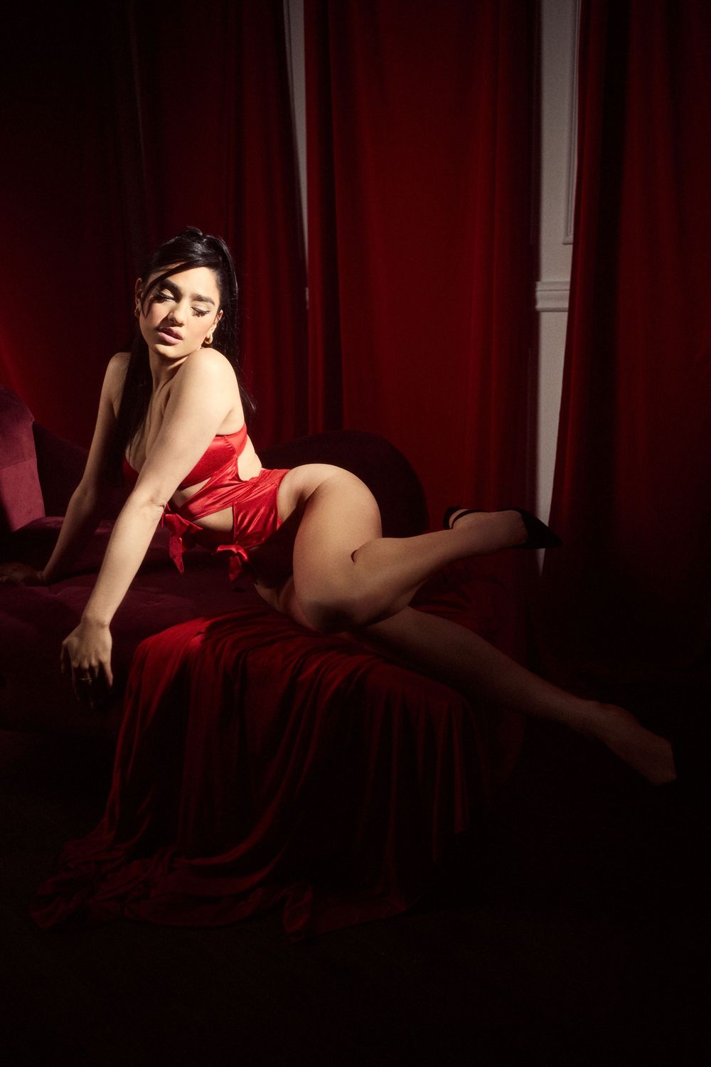 Artistic boudoir photography with deep red drapery and shadows. Light Haus Studio offers luxury wedding, maternity, portrait, and branding p