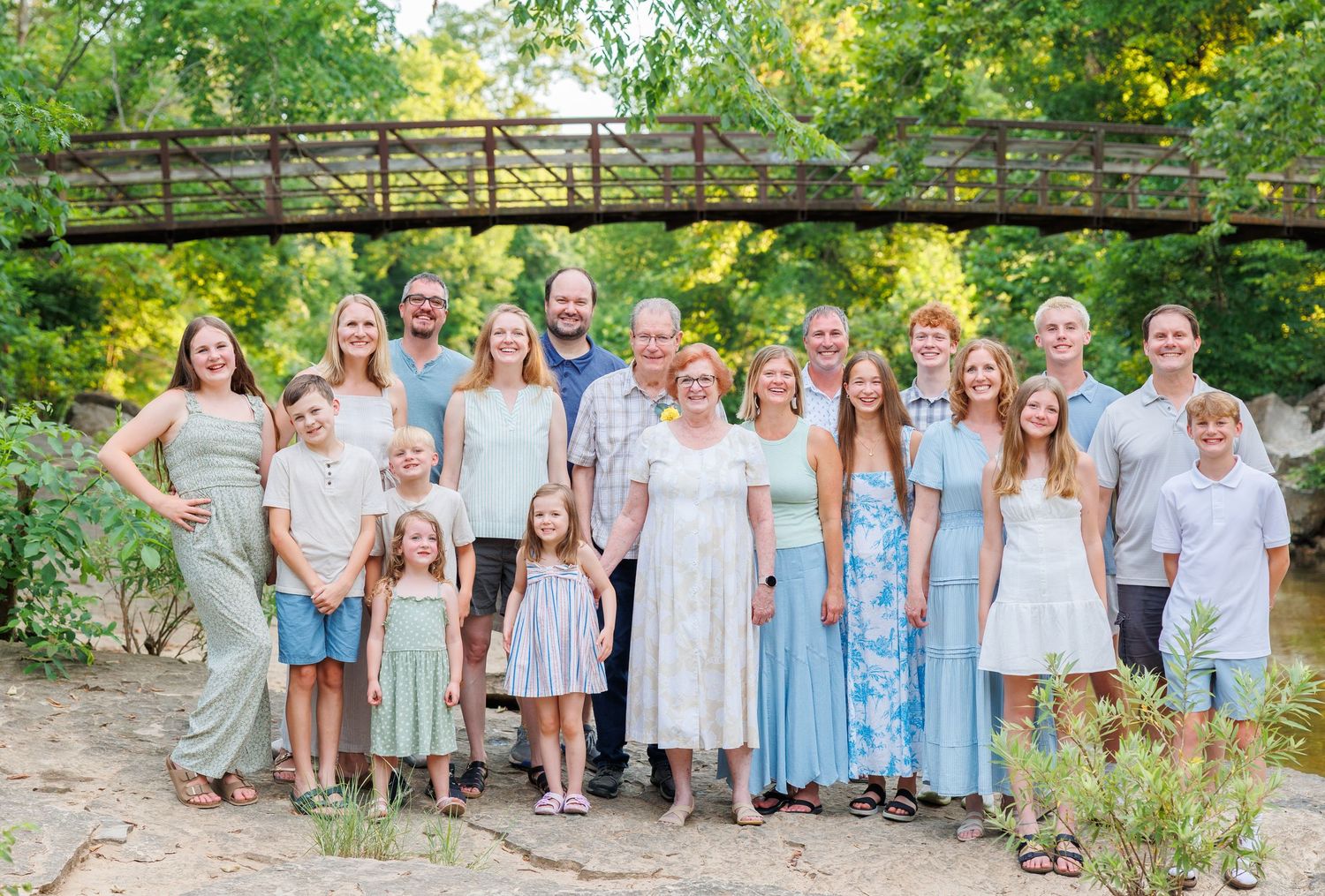 A group wearing coordinated blue and white outfits poses together for outdoor family portraits in a garden setting in Branson, Missouri.