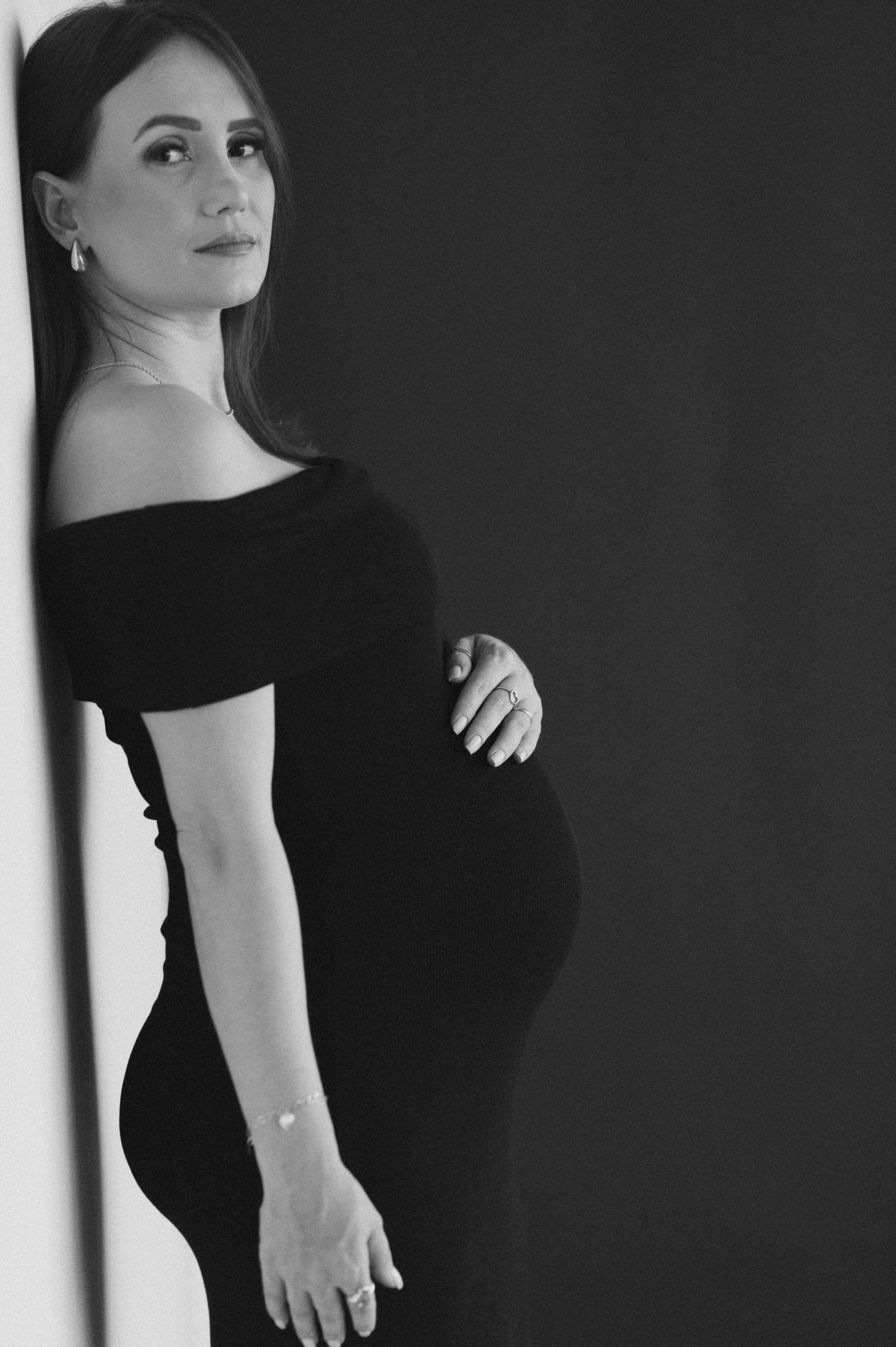 Black and white portrait series showing elegant poses in a little black dress against a minimalist background.