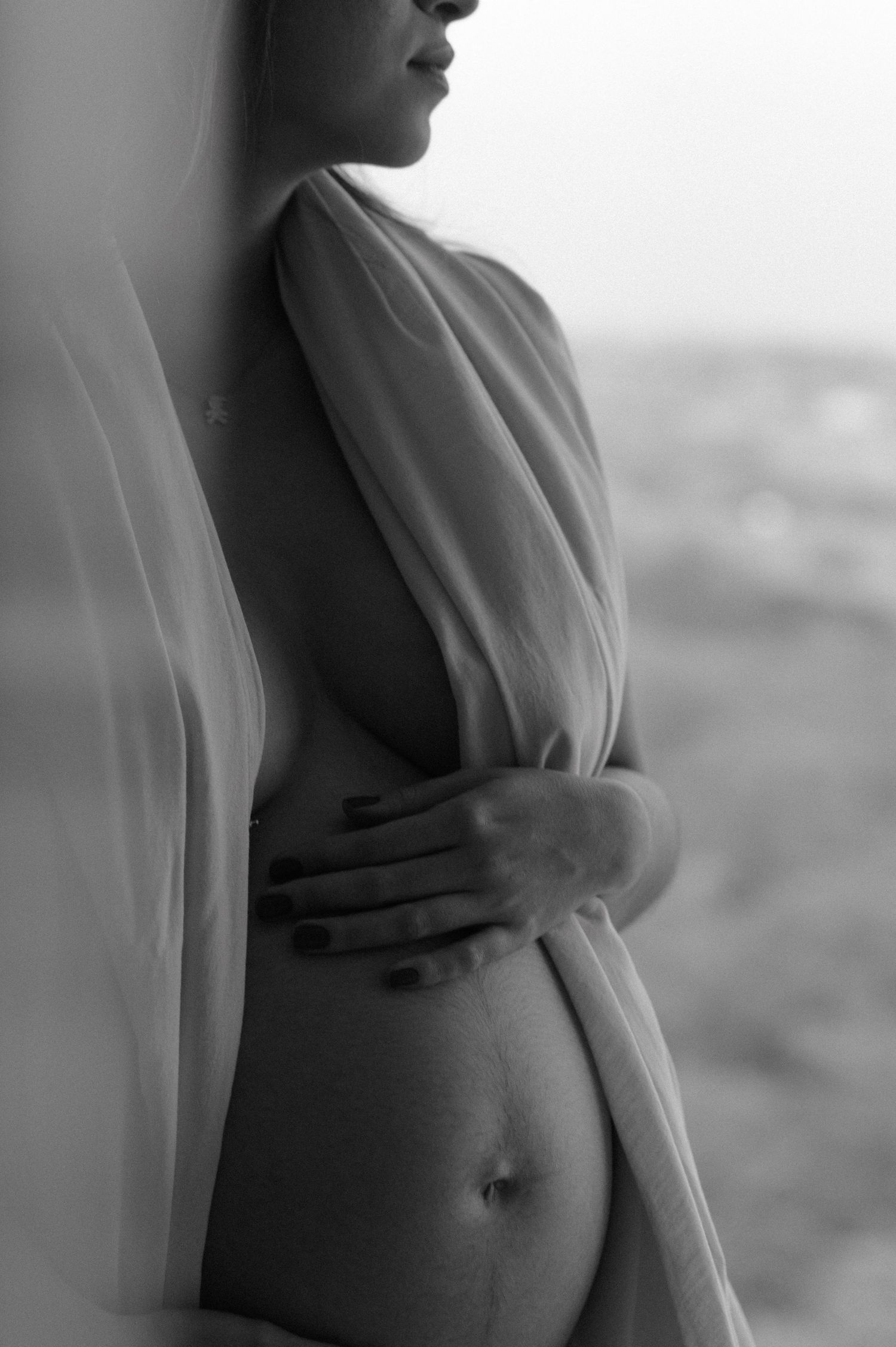 Black and white artistic maternity silhouette series showing a pregnant belly in dramatic lighting.