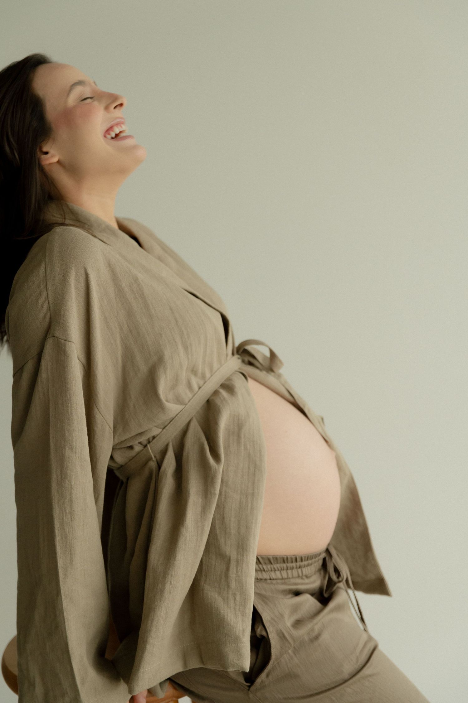 A series of photos showing a pregnant person in a beige jacket posing against a light background.