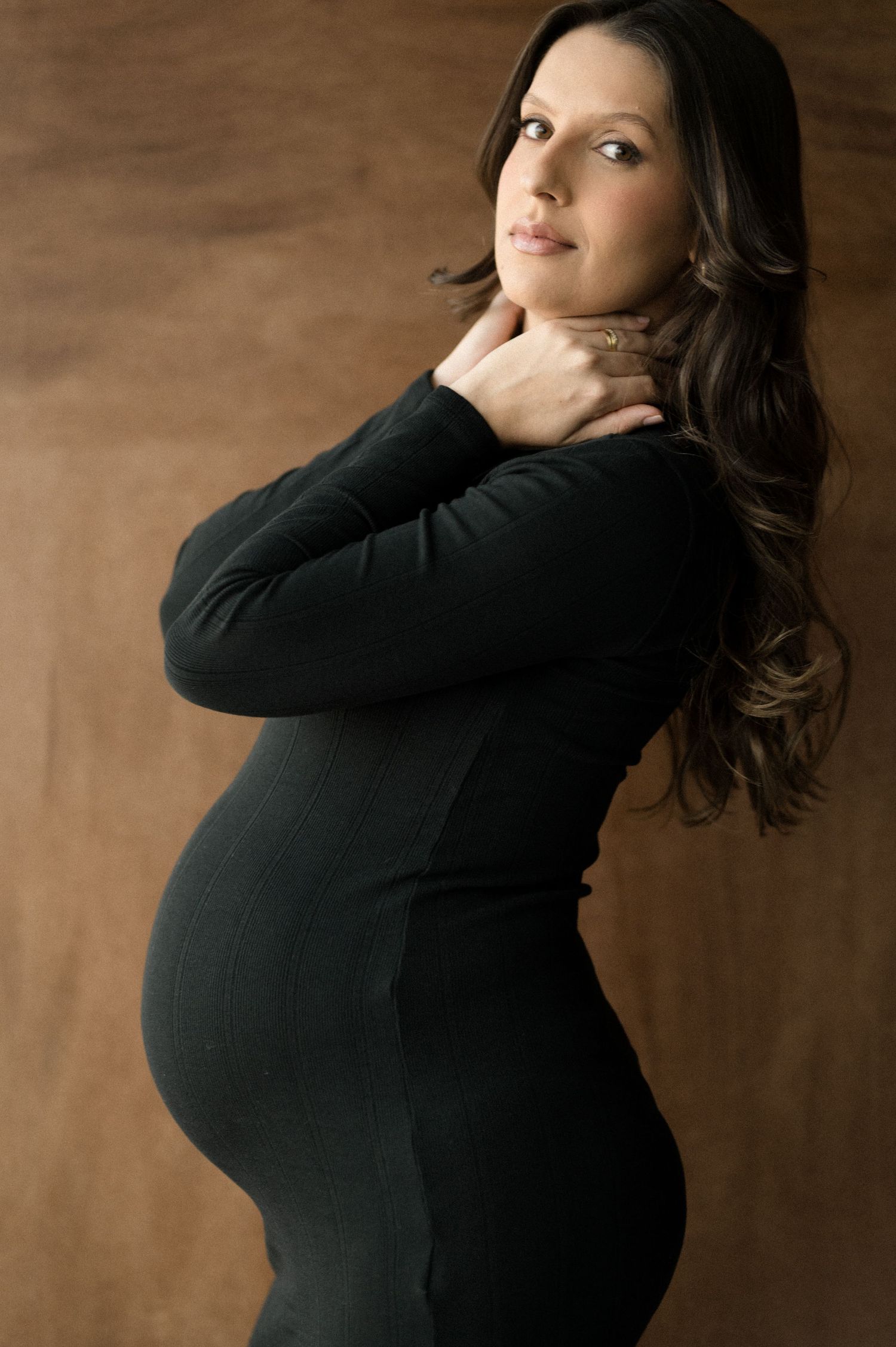 A series of artistic portrait photos showing a woman in a black sweater posing against a brown backdrop.