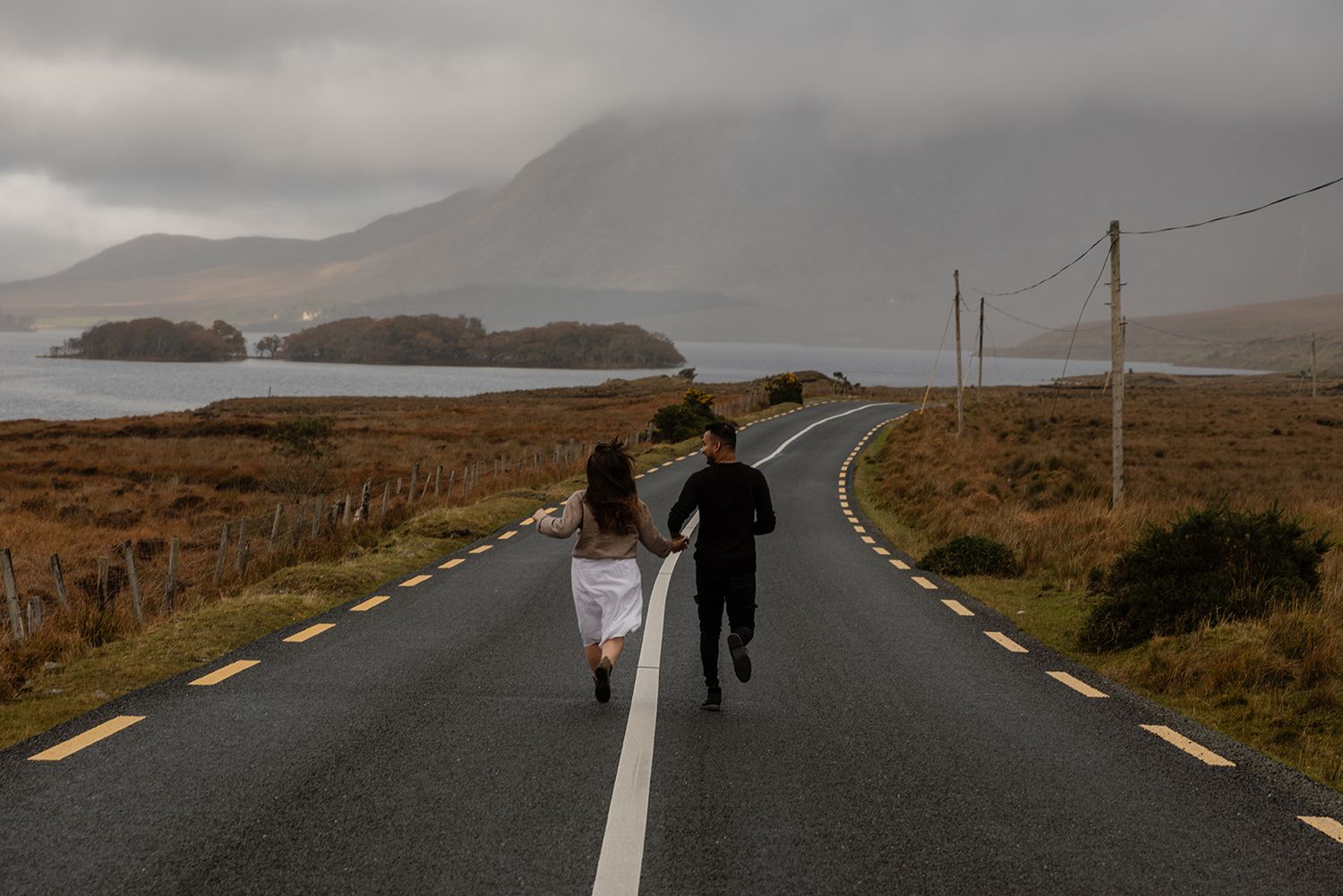 Couple walking hand in hand through Connemara mountain trail during elopement session