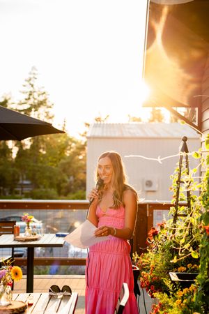 A sunset view of an outdoor patio dining area with flowers and string lights creating a warm ambiance.