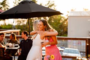 Wedding guests dance and celebrate during an outdoor sunset reception near a swimming pool.