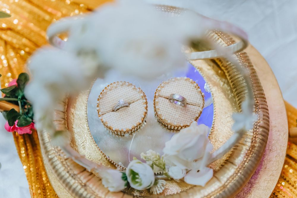Wedding rings displayed on decorative golden plate with white floral accents.