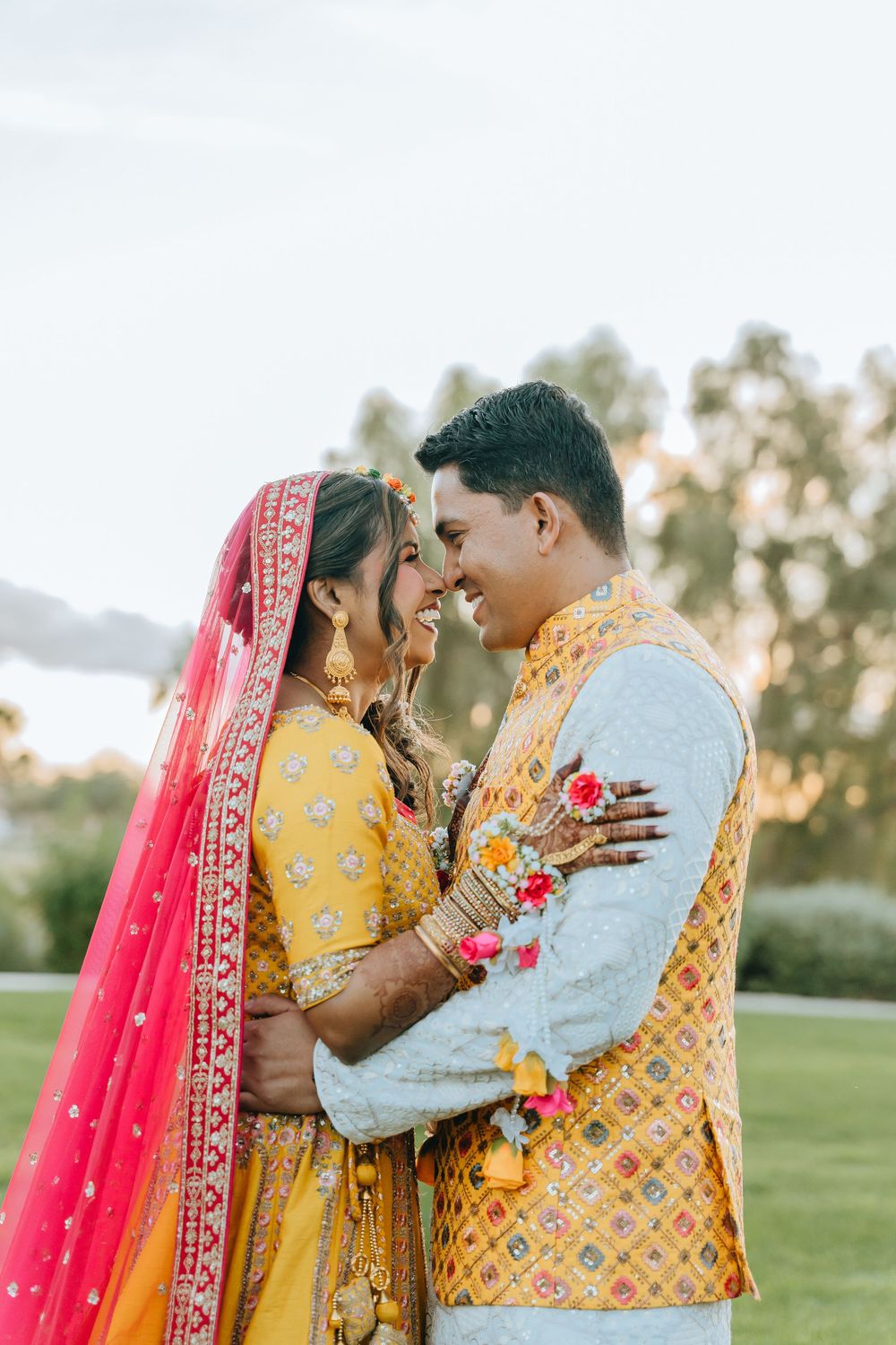 Couple in yellow South Asian wedding attire sharing an intimate moment in a garden.