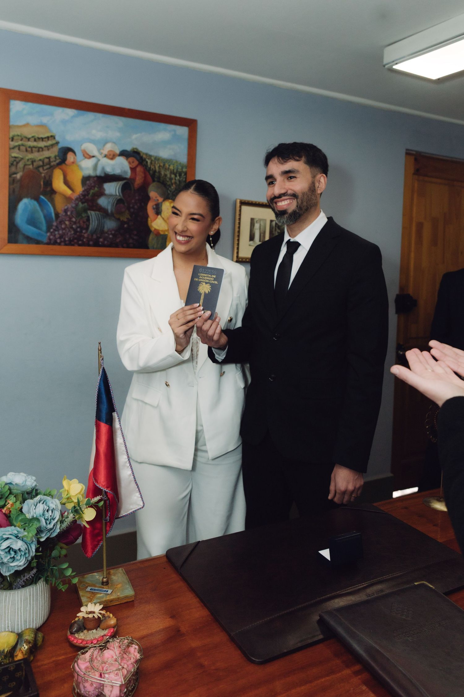 Happy newlyweds posing with marriage certificate after civil wedding ceremony.