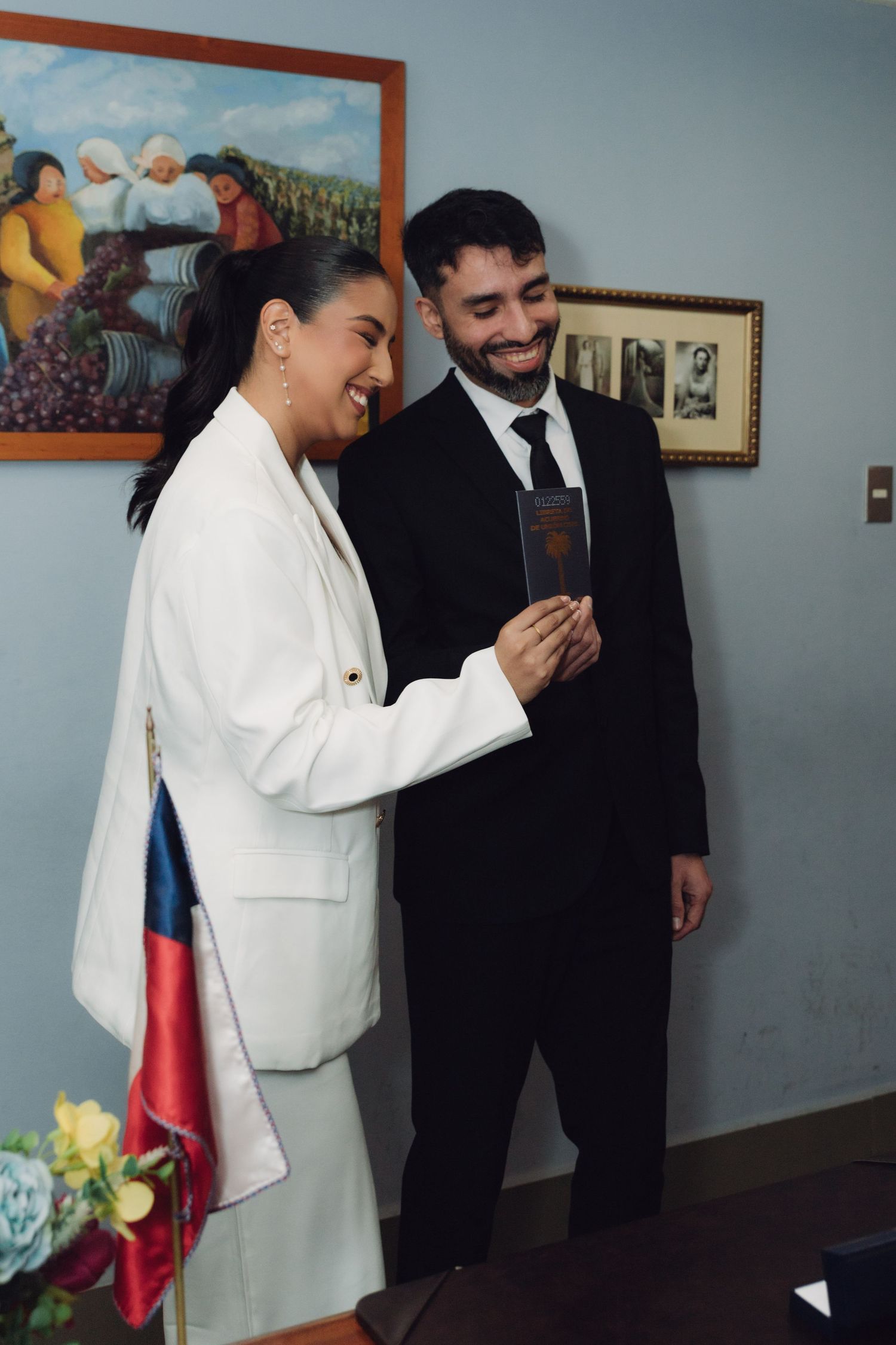 Laughing bride and groom holding marriage booklet after civil wedding ceremony.
