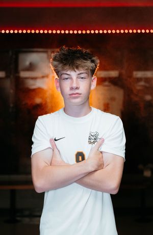 Person in white Nike England jersey poses with crossed arms against dark background with red lighting effects.
