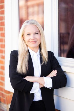 Professional headshots in business attire against a brick wall with white window frames.