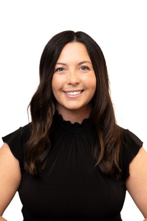 Professional headshot of a smiling woman with dark hair wearing a black sleeveless top against a white background.
