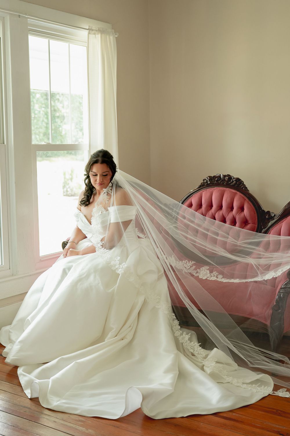 Artistic bridal portraits showing movement of a white wedding gown and veil against hardwood floors.