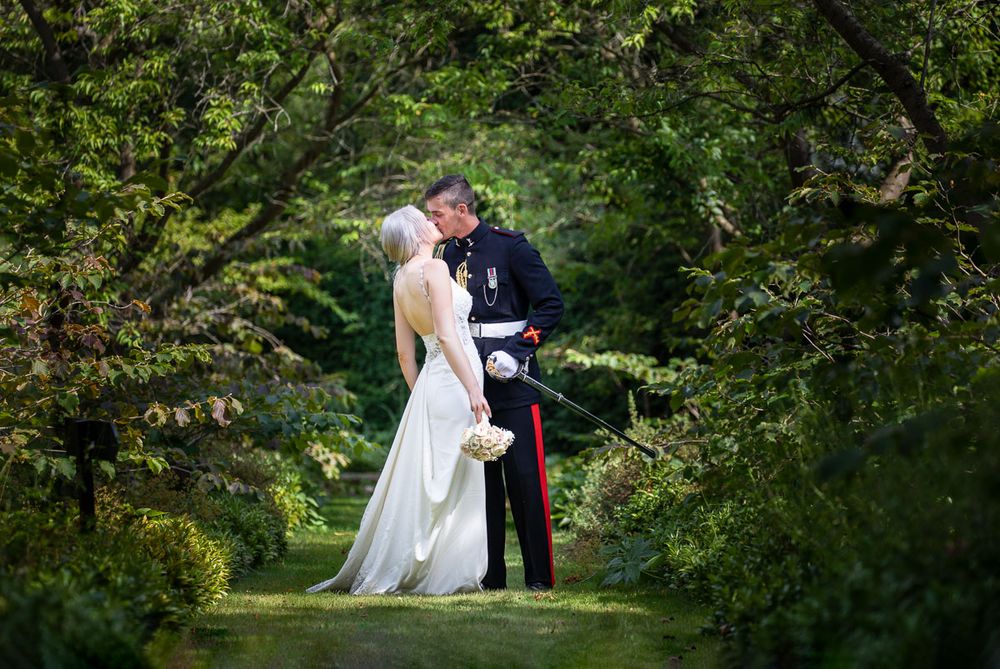 A romantic wedding couple shares a tender moment in the lush gardens of Allington Castle in Kent.