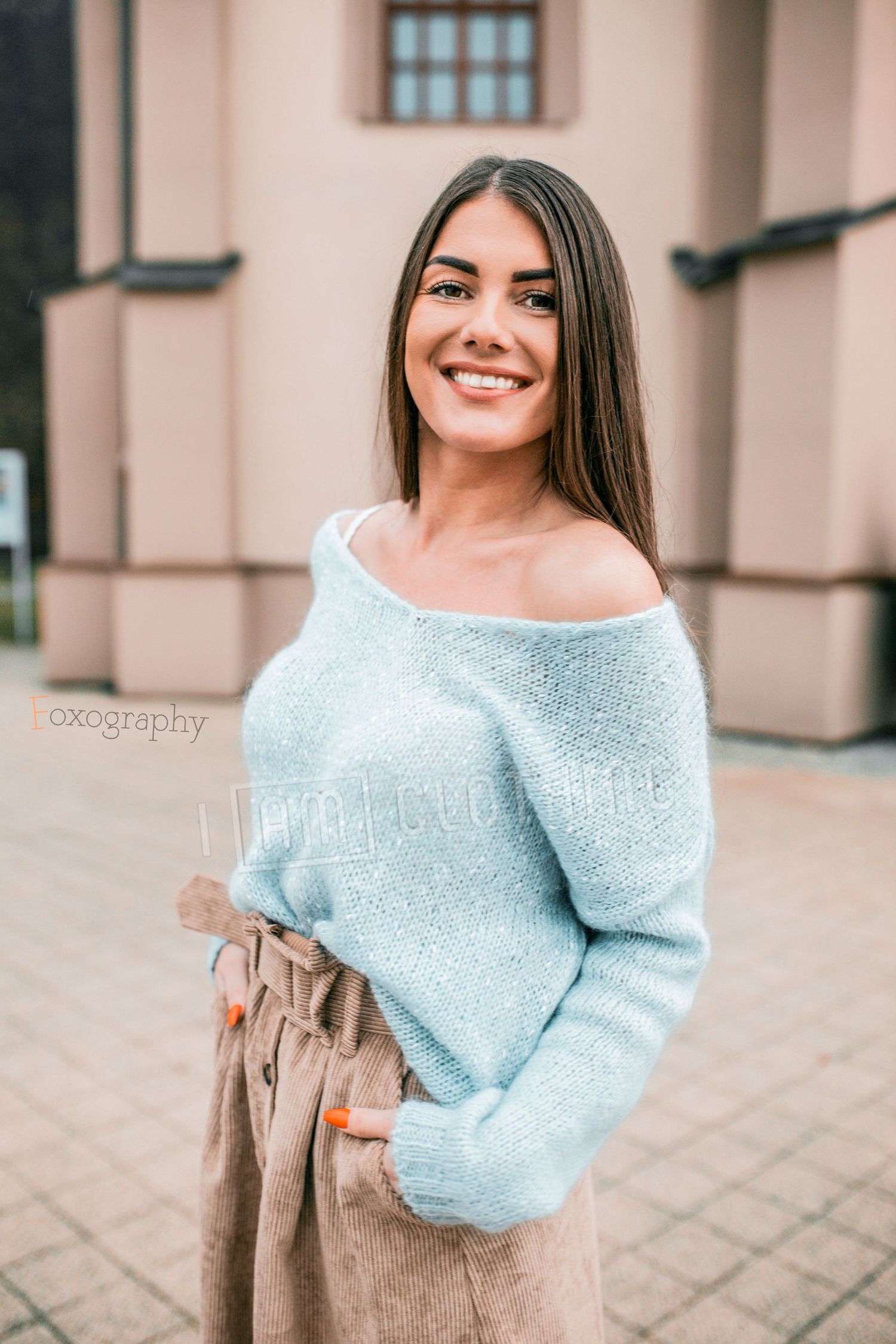 Usmievavá mladá žena v jesennom outfite pred historickou budovou. Profesionálna exteriérová fotografia v Žiline.