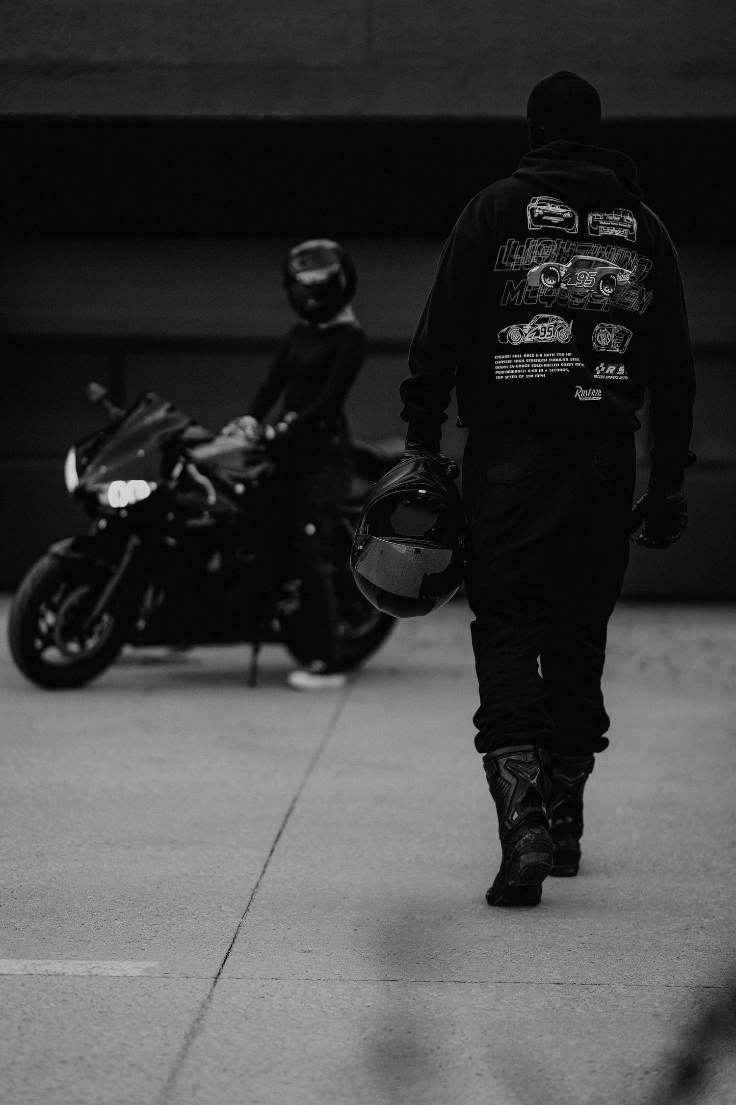 Postava muža v motorkárskom oblečení kráčajúceho smerom k motorke, lifestylová fotografia s nádychom slobody.
