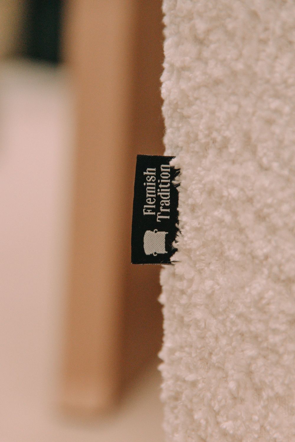 Close-up van een label van het merk Flemish Tradition, genaaid op een zachte witte stof.