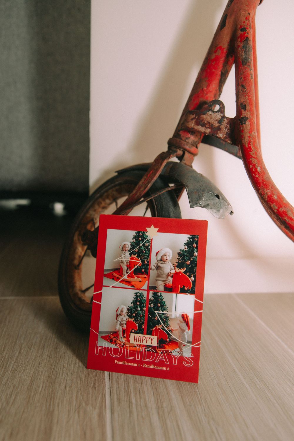 Een kerstkaart die tegen een vintage roestrode fiets leunt | Brandingfoto
