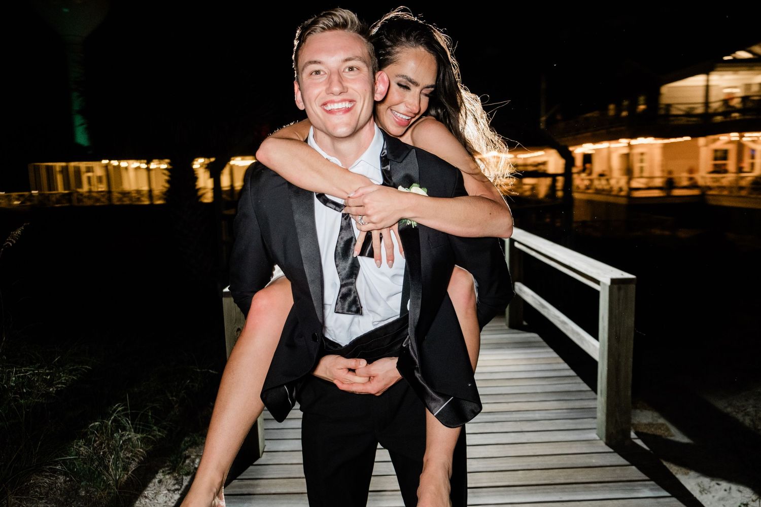 A group of wedding guests dancing and celebrating on a dark dance floor at a reception party.