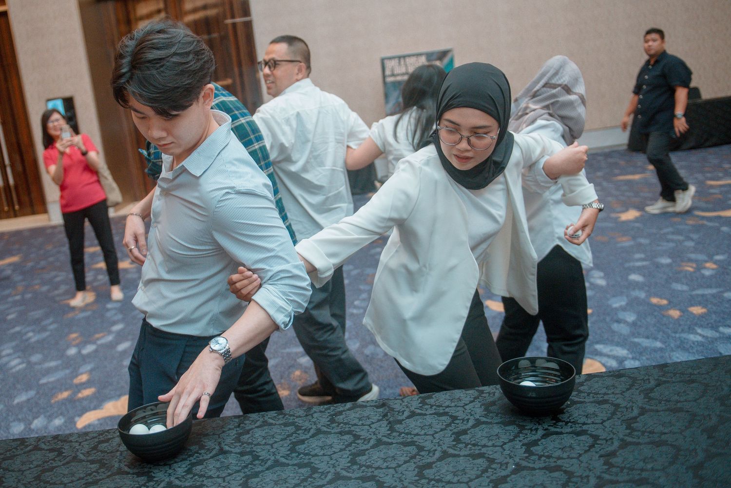 A group of people practicing martial arts moves on a carpeted floor in a studio space.