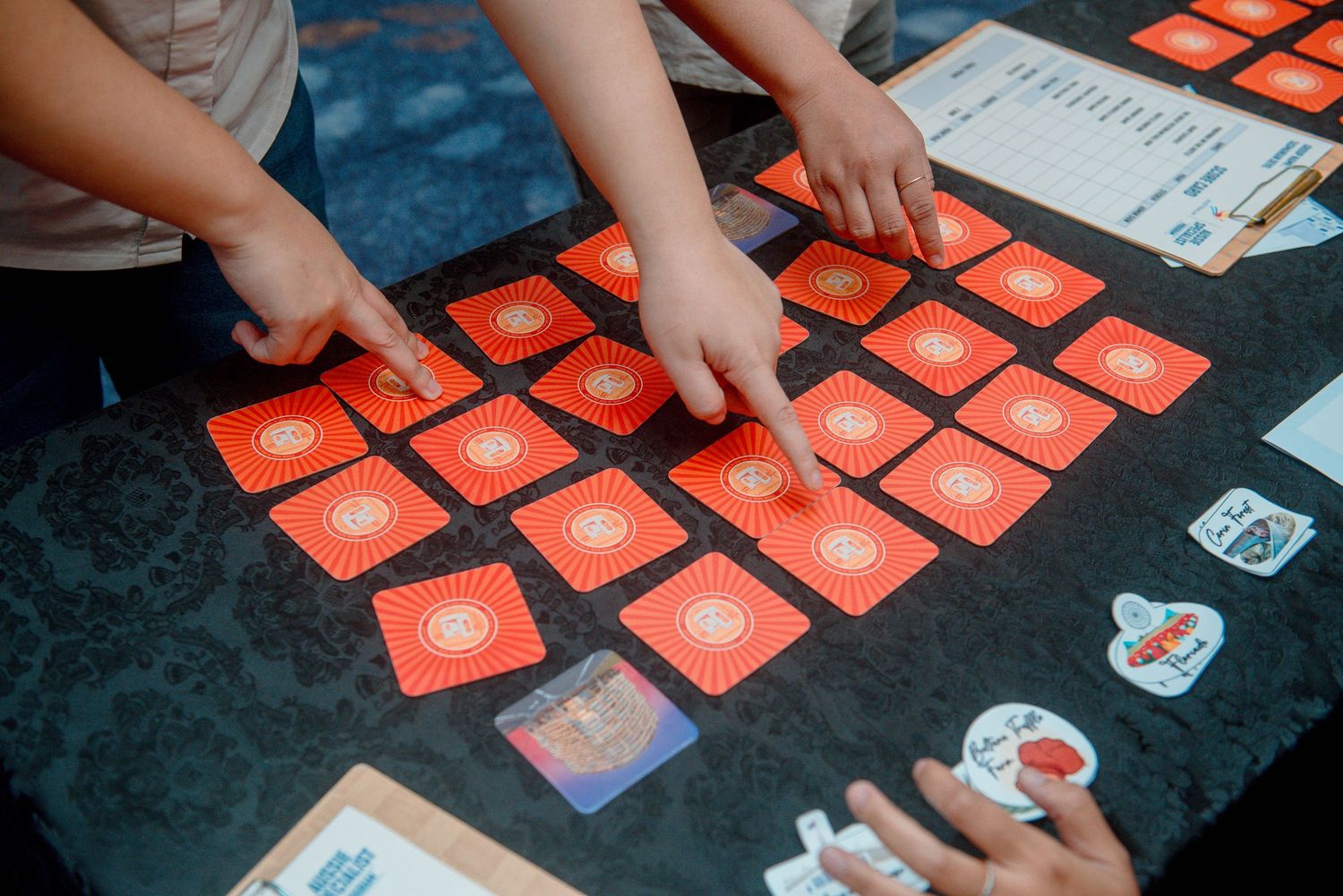 Hands arranging red cards on a dark surface during a card game or activity session.