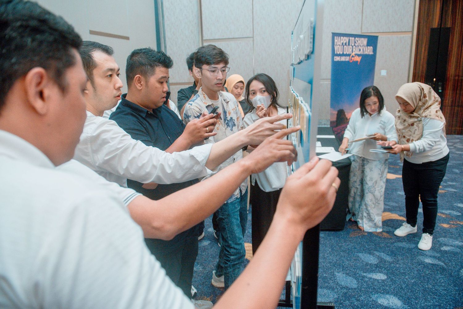 A group of people stand in line at a restaurant while looking at their mobile phones during a break.
