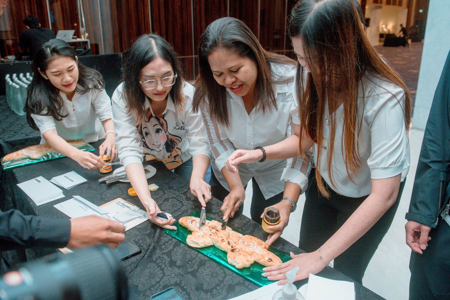 A group of people sitting together at a table learning to make sushi rolls during a cooking class.