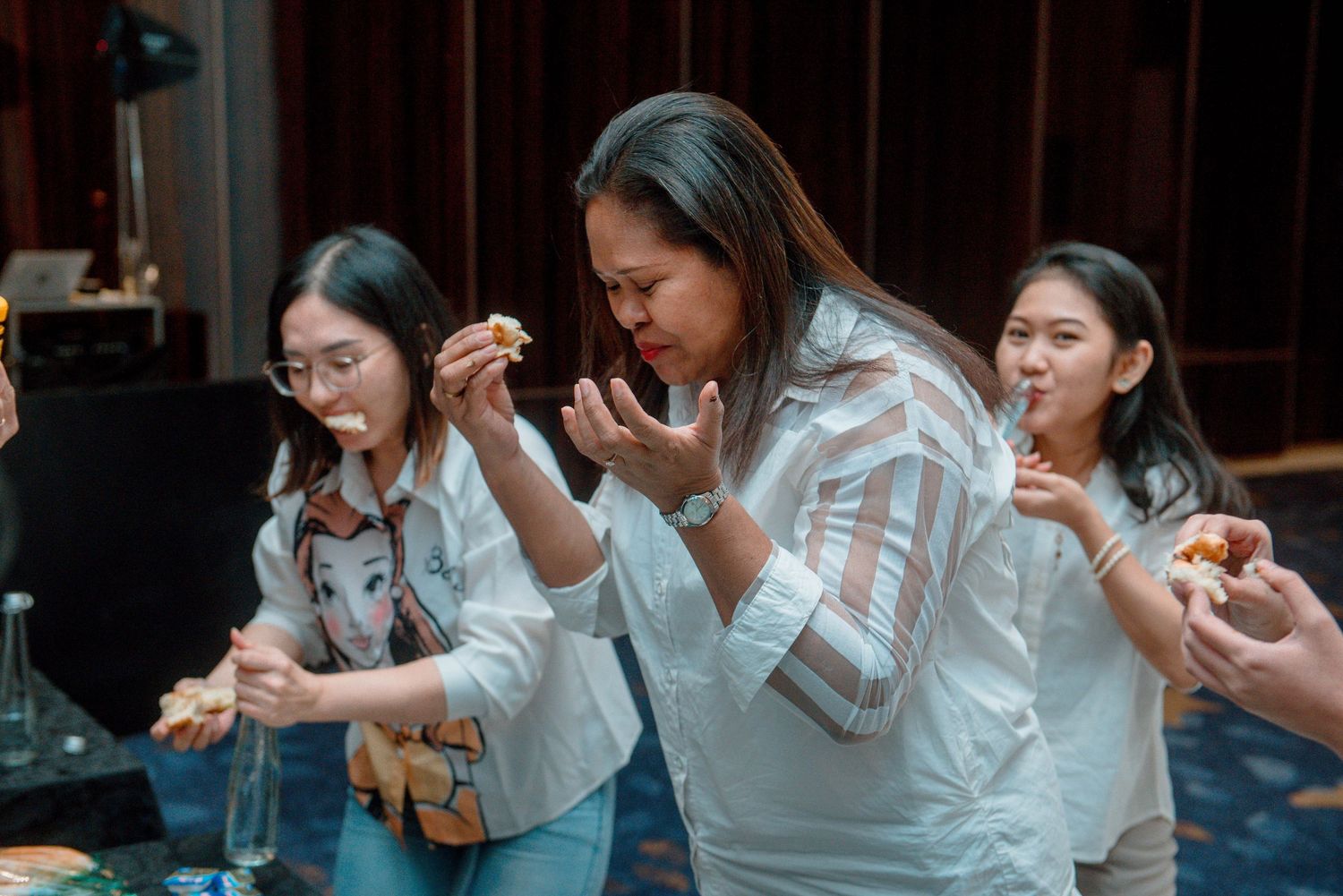 Group of people in white shirts sitting at a table using mobile phones during a social gathering.