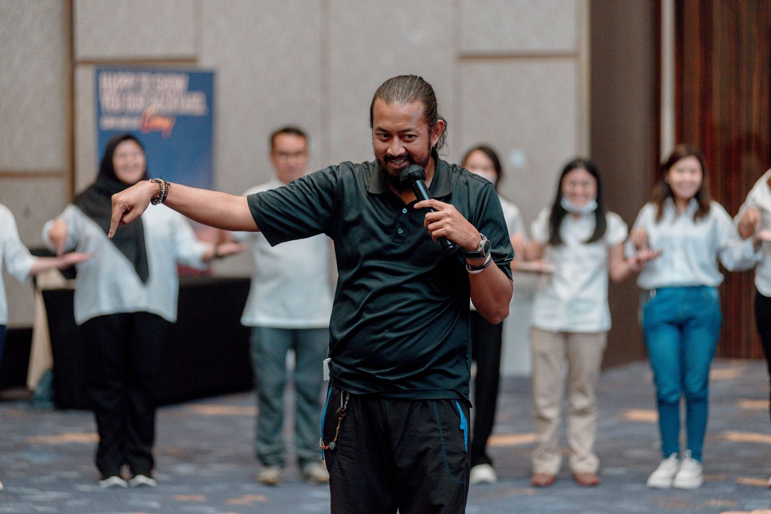 A person in a black shirt performs an energetic dance move in front of a crowd.