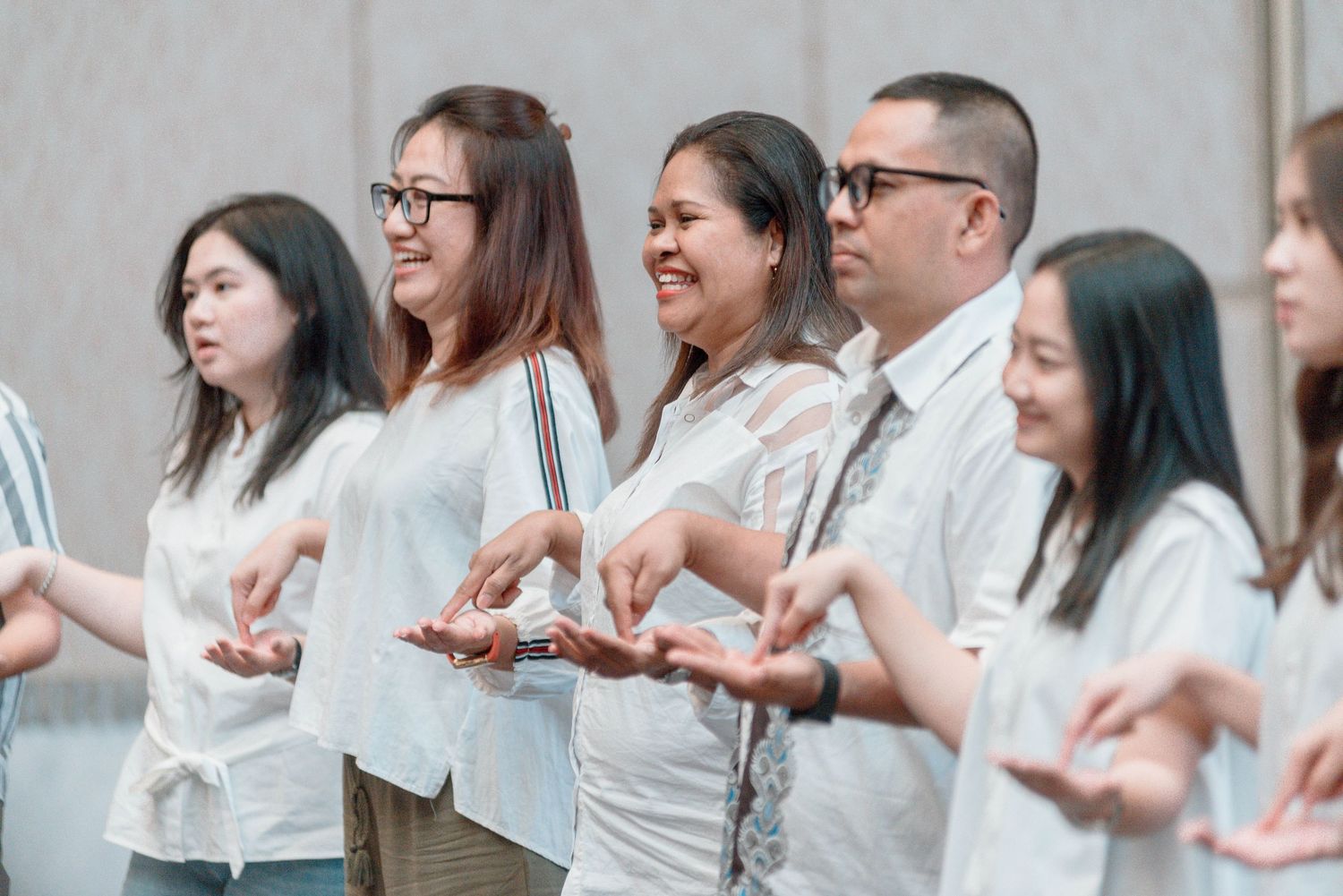 People in casual attire form a connected line while participating in a collaborative workshop activity.